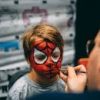 A child enjoys festival face painting with a bold Spider-Man design.